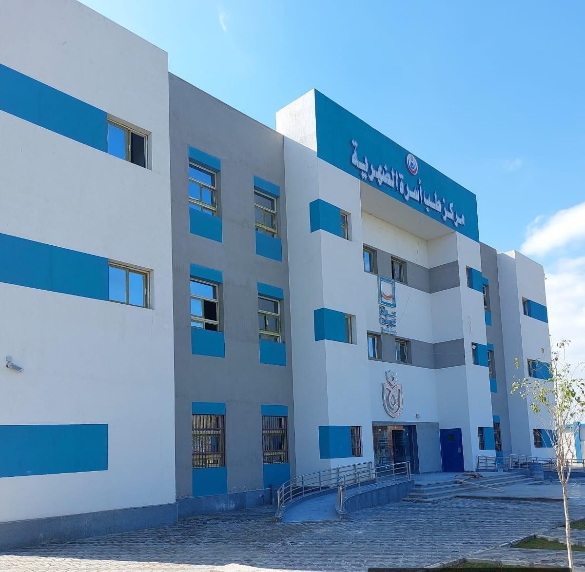 Exterior view of a modern multi-story healthcare building with blue accents and signage in Arabic.