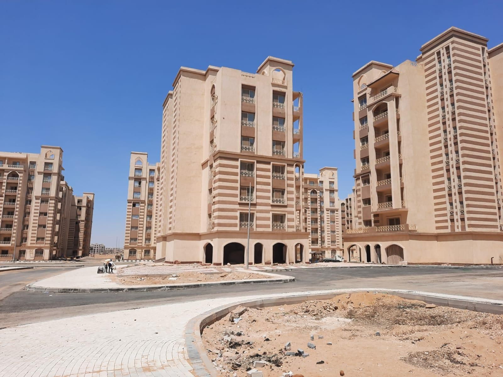 Group of new beige residential buildings with striped details under a clear blue sky.